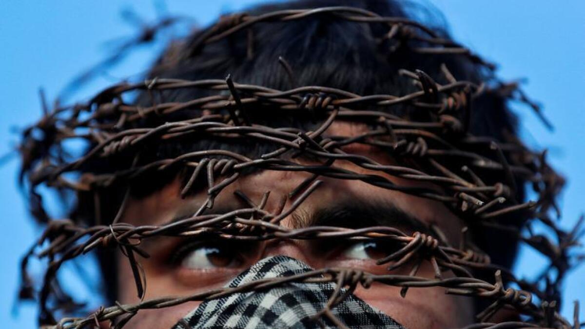 A masked Kashmiri man with his head covered in barbed wire attends a protest after Friday prayers, during restrictions following the scrapping of the special constitutional status for Kashmir by the Indian government, in Srinagar, October 11, 2019. - Reuters