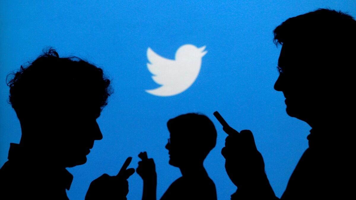 People holding mobile phones are silhouetted against a backdrop projected with the Twitter logo.- Reuters file photo