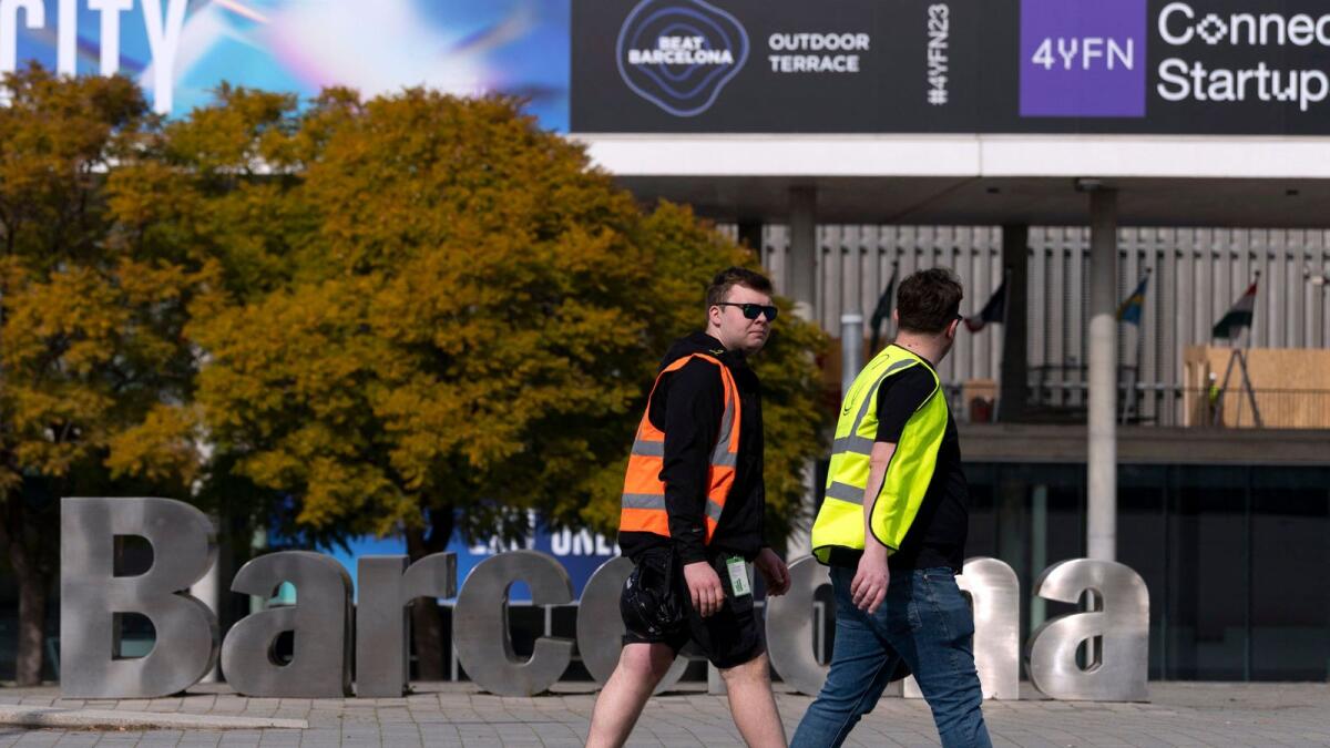 Two workers walk past the entrance of Fira Barcelona, venue of the Mobile World Congress (MWC) — the world's largest connectivity event. The five-day event will continue until March 2, 2023. — AFP