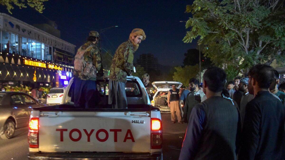Taliban fighters stand on a pickup truck outside a hospital as volunteers bring injured people for treatment. Photo: AFP
