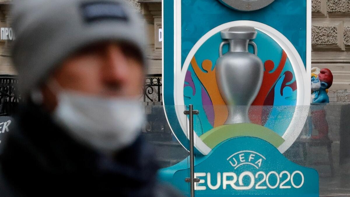 A man wearing a protective face mask walks past the Euro 2020 countdown clock in Saint Petersburg, Russia (AFP)