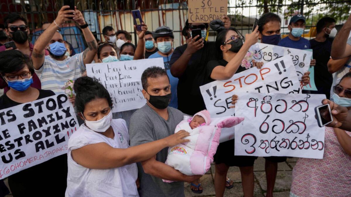 A Sri Lankan couple with their infant join an anti government protest during a curfew in Colombo. — AP