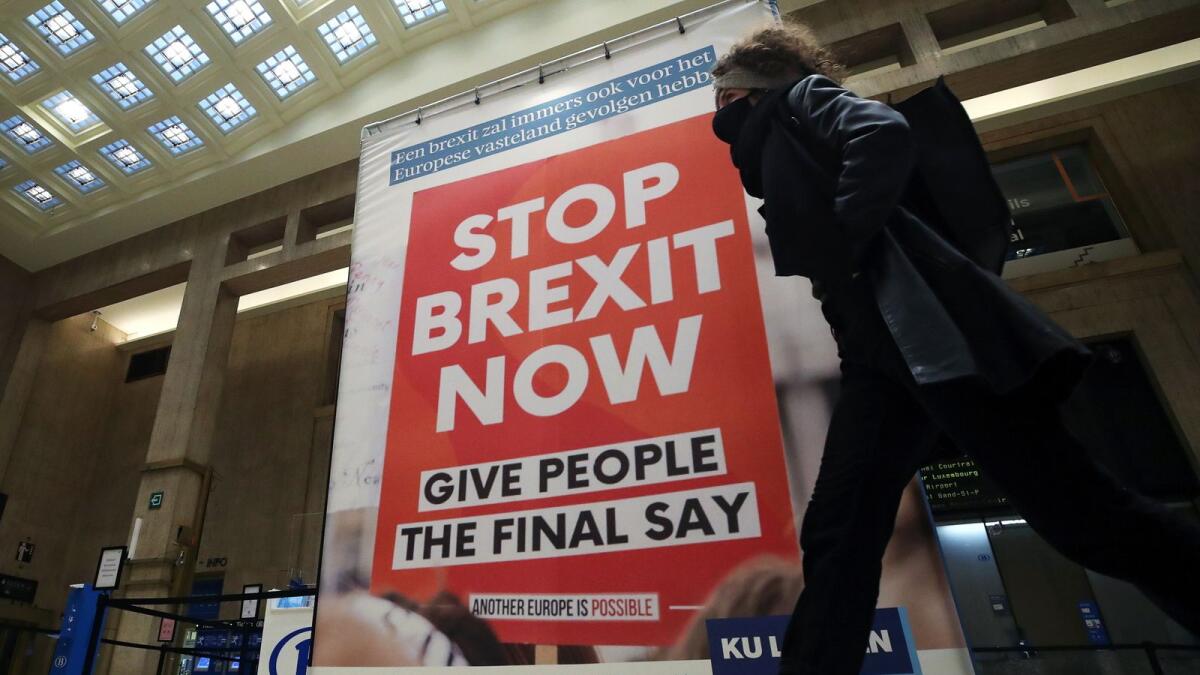 A woman walks past a billboard depicting a photo of a placard reading 'Stop Brexit Now' at the Central railway station in Brussels, Belgium December 17, 2020.
