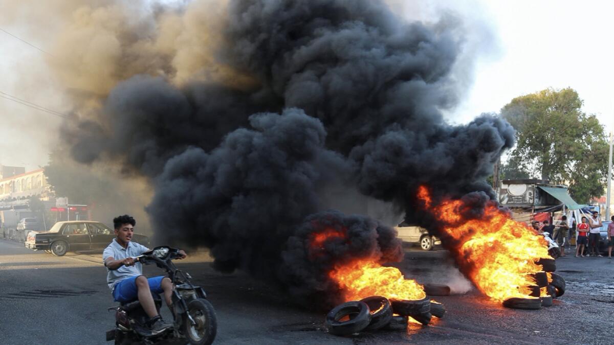 A youth man boy rides his motorbike near burning tires during a sit-in protest against the fall in pound currency and mounting economic hardship, in Ghazieh, south of Lebanon. Photo: Reuters