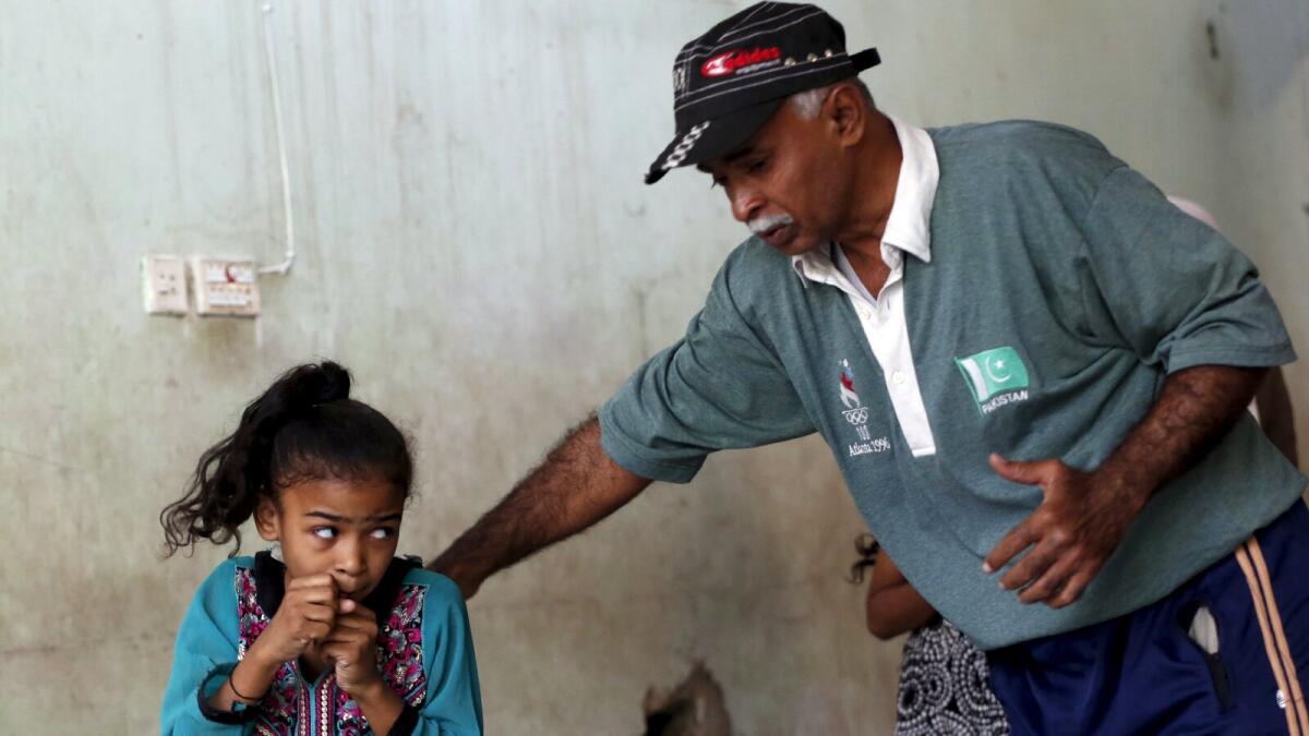 Arisha, 9, takes instructions from coach Younus Qambrani during an exercise session at the first women's boxing coaching camp in Karachi, Pakistan February 19, 2016.