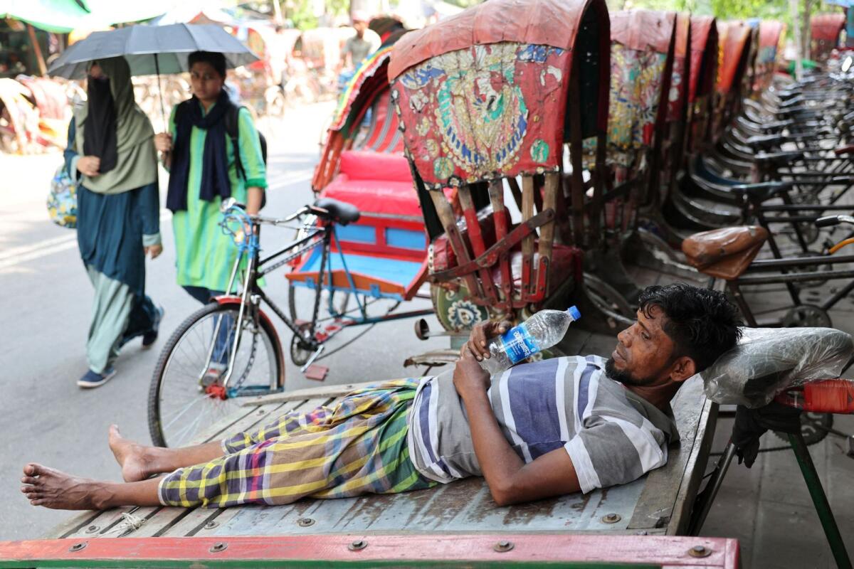 A man rests on a cart during a heatwave in Dhaka, Bangladesh. — Reuters
