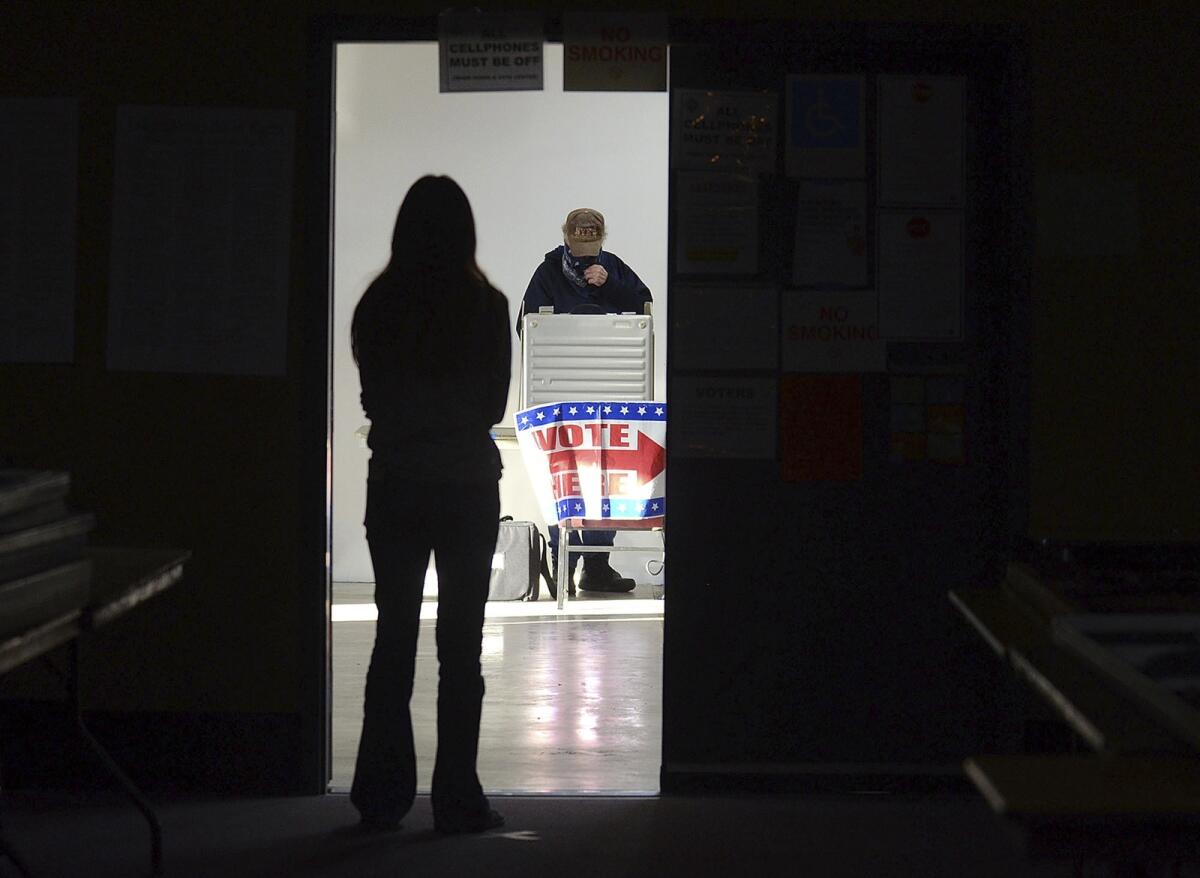 A first-time voter waits in the doorway for a voting booth as another voter completes his ballot at the Boot City Opry near Terre Haute, Indiana, on November 3, 2020. — AP