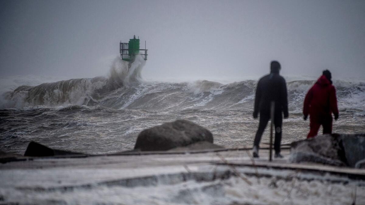 People stand next to the sea to watch high waves as a violent storm Otto hits Thorsminde in West Jutland, Denmark. — AFP