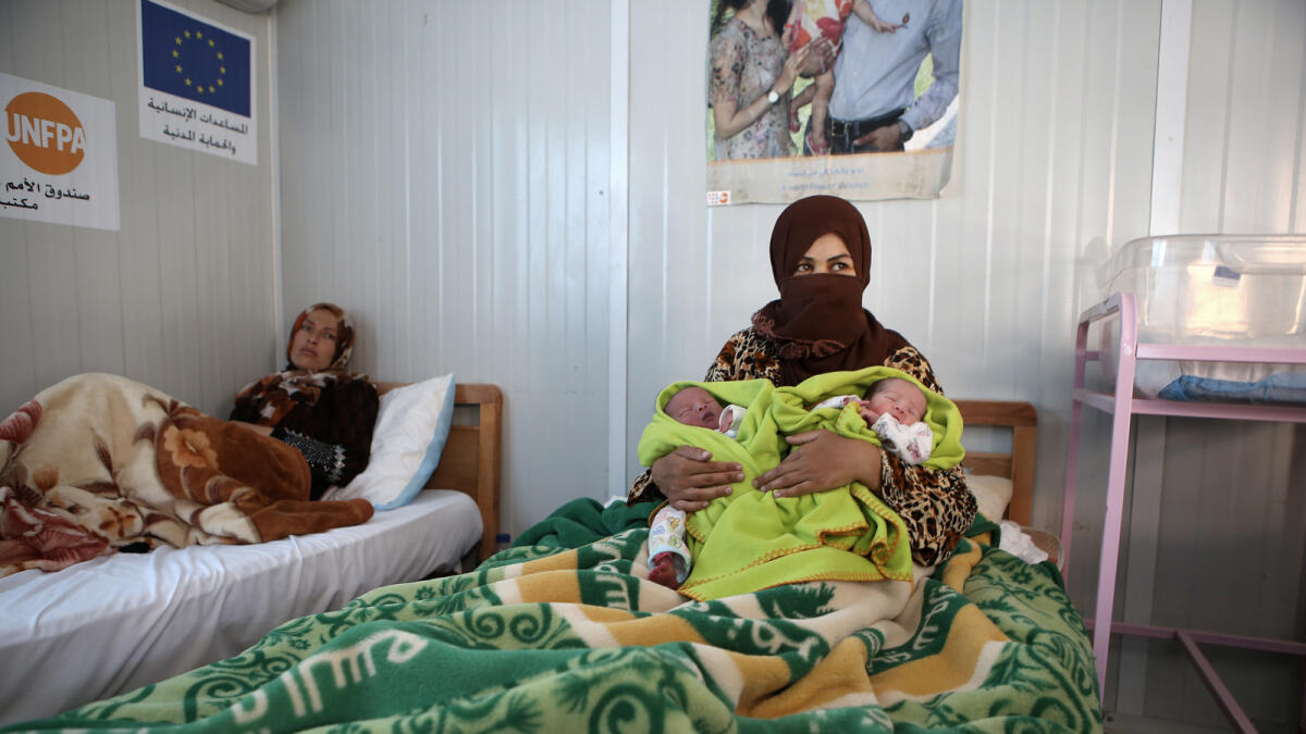 Syrian refugee Maan Turkman, 31, holds her twin infants Mohammed, left, and Ahmed, at a maternity clinic in Zaatari refugee camp.