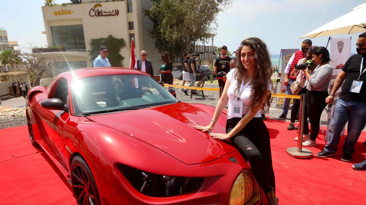 A model leans on the hood of the 'Quds Rise', the first ever electric car produced in Lebanon, during an unveiling ceremony in Khaldeh, south of the capital Beirut, on Saturday.