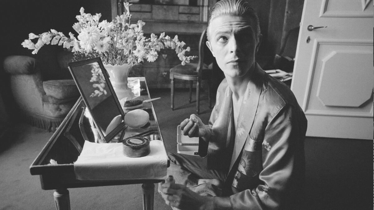 David Bowie prepares his makeup in his hotel suite prior to an impromptu photo shoot that morning in Paris (1976)