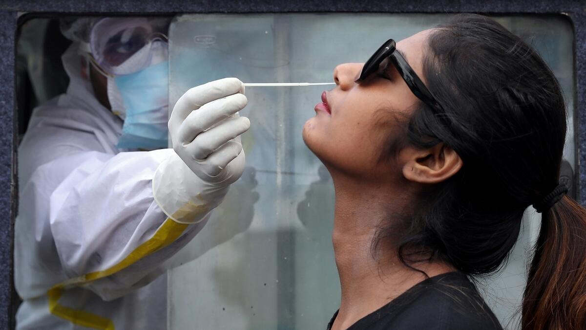 A healthcare worker inside an ambulance takes a swab from a woman to test for Covid-19, in Kolkata.