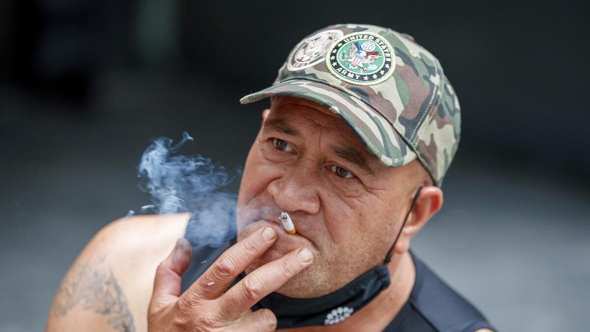 A man sits while smoking in Auckland, New Zealand on Dec. 9, 2021. New Zealand on Tuesday passed into law a unique plan to phase out tobacco smoking by imposing a lifetime ban on young people buying cigarettes. — AP