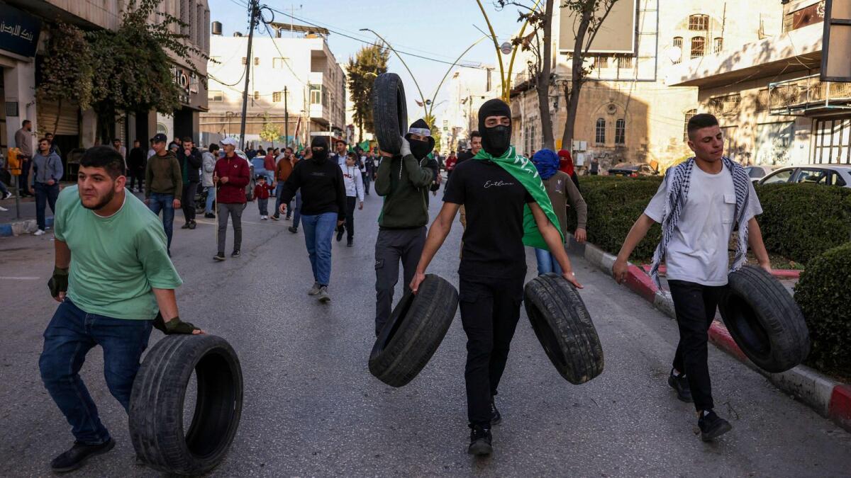 Palestinian protestors carry tyres during a rally supporting the Gaza Strip in the occupied West Bank city of Hebron. — AFP