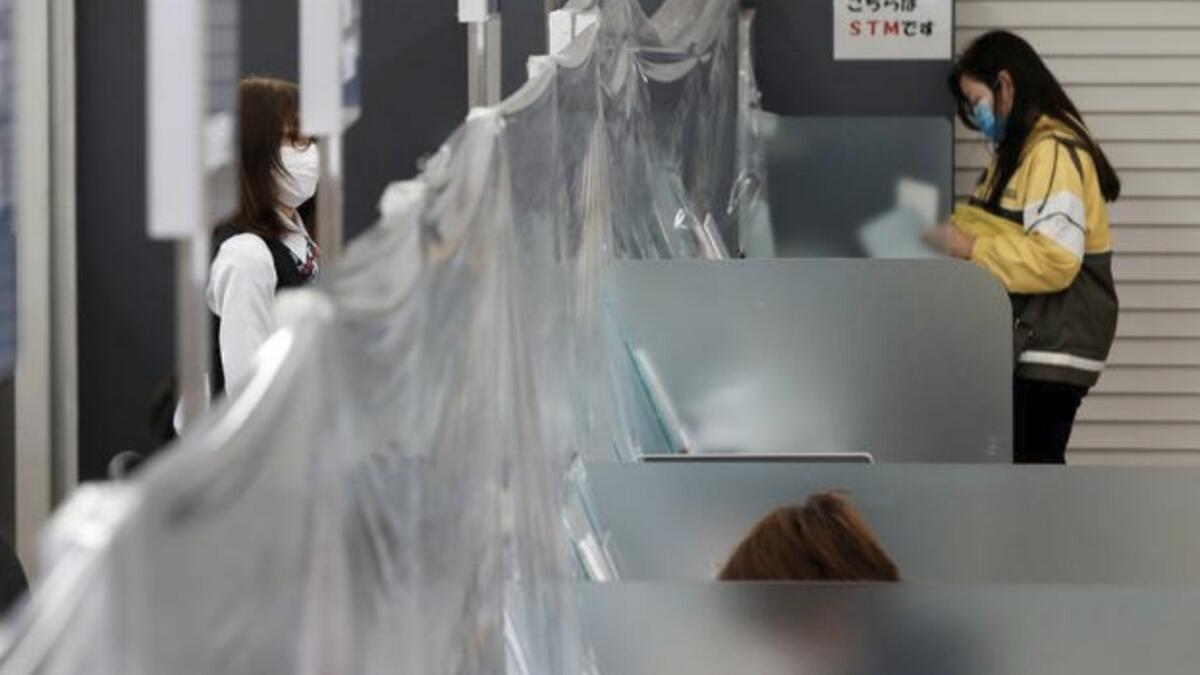 A bank teller wearing a protective face mask stands at a counter where a plastic curtain is installed at the Higashinakano branch of MUFG Bank in Tokyo. Reuters
