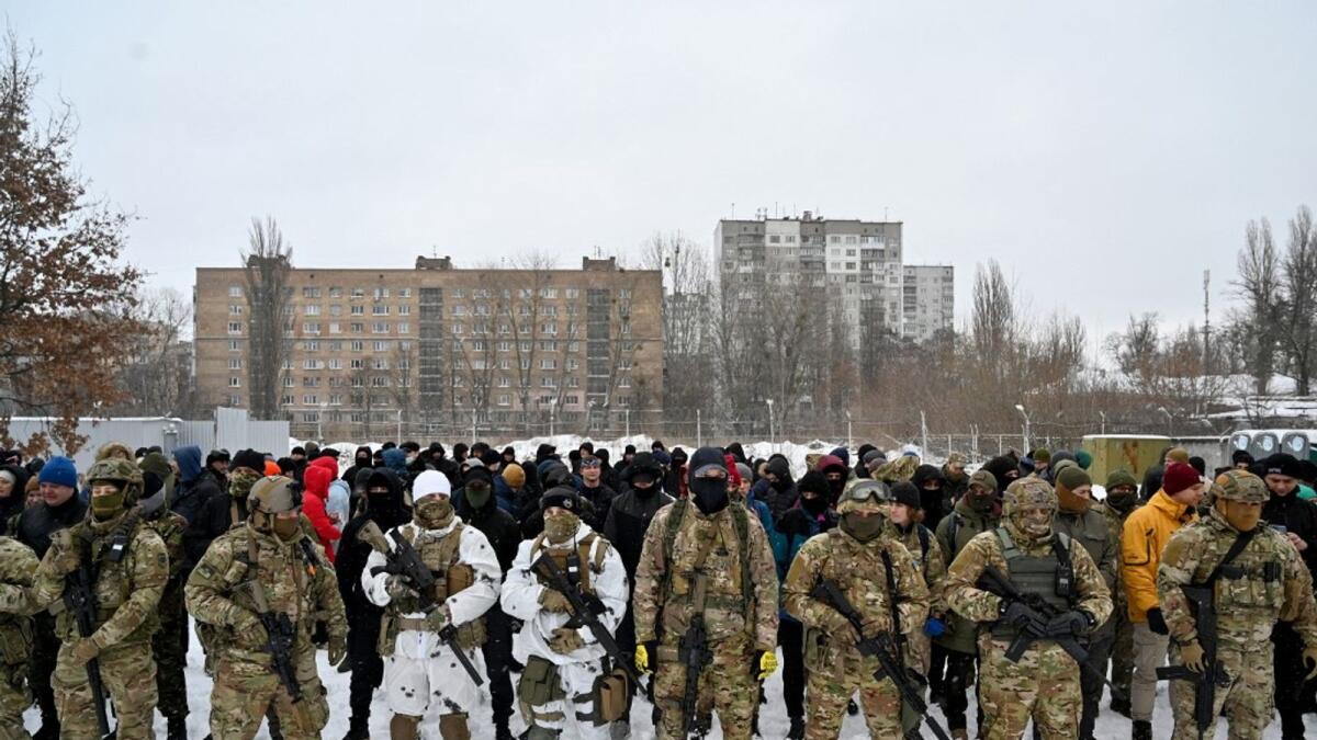Military instructors and civilians stand prior to a training session at an abandoned factory in the Ukrainian capital of Kyiv on January 30, 2022. - As fears grow of a potential invasion by Russian troops massed on Ukraine's border, within the framework of the training there were classes on tactics, paramedics, training on the obstacle course. The training is conducted by instructors with combat experience, members of the public initiative 'Total Resistance'. (Photo by Sergei SUPINSKY / AFP)