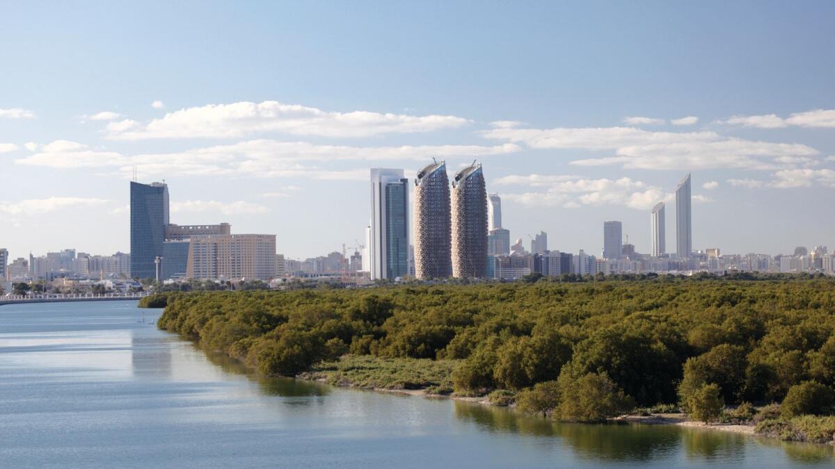 Skyline of Abu Dhabi Al Reem Island with mangrove forest in foreground.