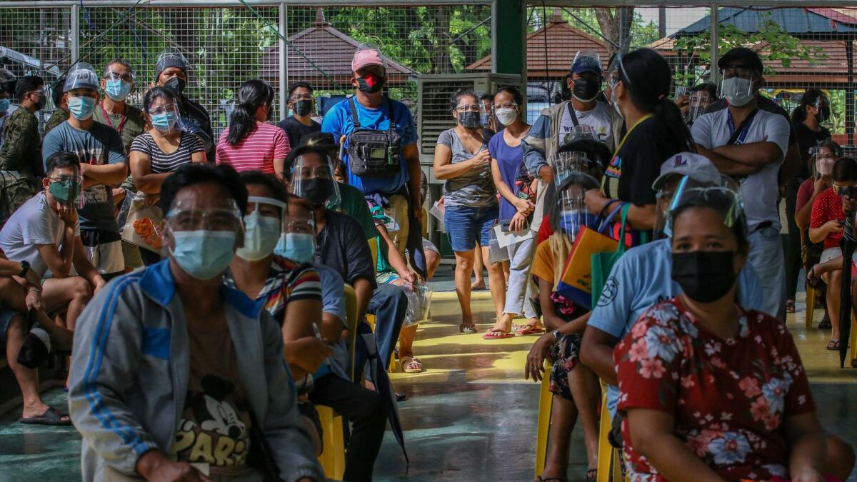 People line up to receive cash aid from the government during enhanced community quarantine in Manila. Photo: AFP