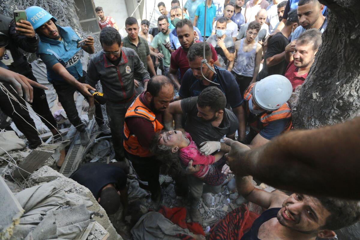 Journalists, left, report as Palestinians rescue a child from under the rubble after Israeli airstrikes in Gaza City, Gaza Strip, Wednesday, Oct. 18, 2023. AP