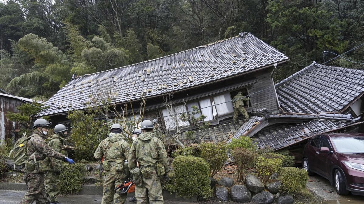 Japanese Self Defence Force members inspect a collapsed house hit by earthquakes in Suzu. — AP