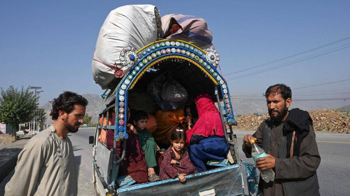Afghan nationals along with their families stand along a road near a vehicle in Jamrud area of Khyber district, some 30km west of Peshawar, as they return to Afghanistan following Pakistan's government decision to expel people illegally staying in the country. — AFP File