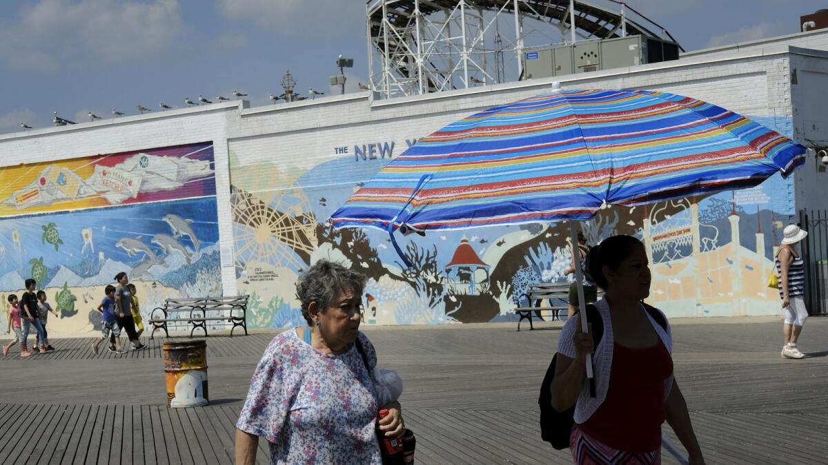 People walk along the Coney Island boardwalk on a hot afternoon in the Brooklyn borough of New York City. Photo: AFP