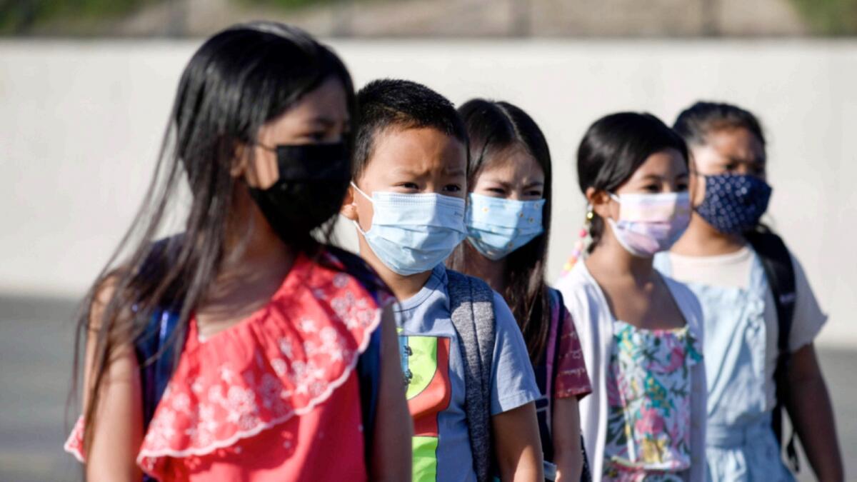 Masked students wait to be taken to their classrooms at a school in California. — AP file