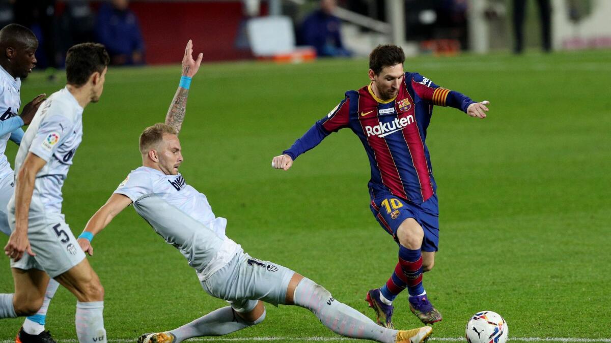Lionel Messi in action with Valencia's Uros Racic. — Reuters