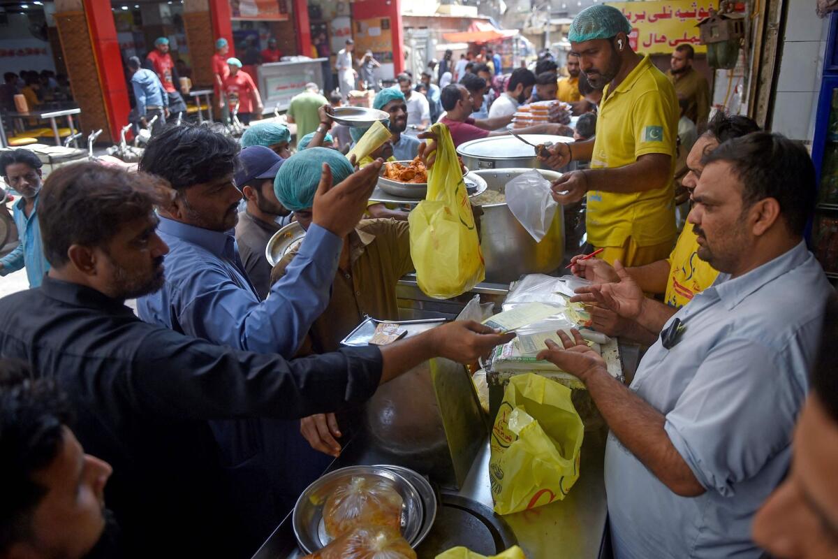 People buy biryani at a restaurant in Karachi. Eying each other across a stream of traffic, rival Pakistani biryani joints vie for customers, serving a fiery medley of meat, rice and spice that unites and divides South Asian appetites. — AFP