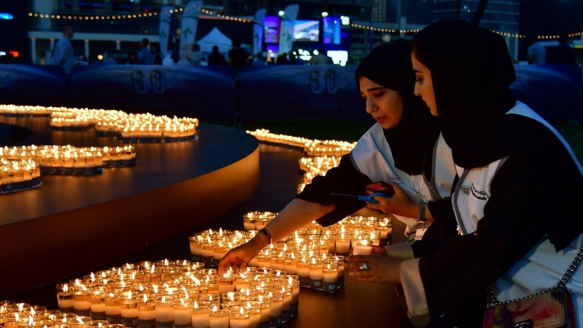 Two women light candles after the building lights were switched off for the Earth Hour environmental campaign in Dubai on March 24, 2018.  AFP