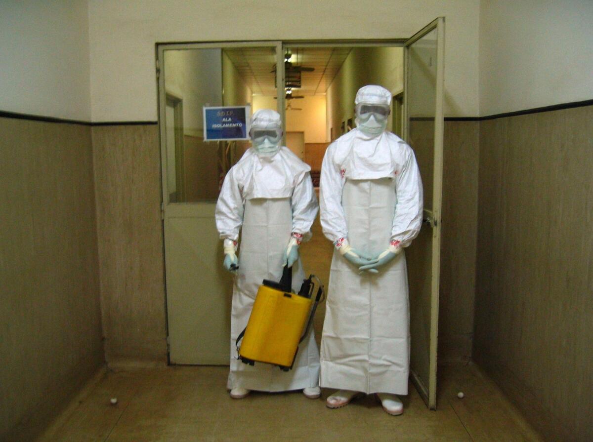 FILE. Two health workers, wearing protection outfits, leave the isolated area where people infected by the deadly Marburg virus are treated at the Americo Boa Vida hospital. Photo: AFP