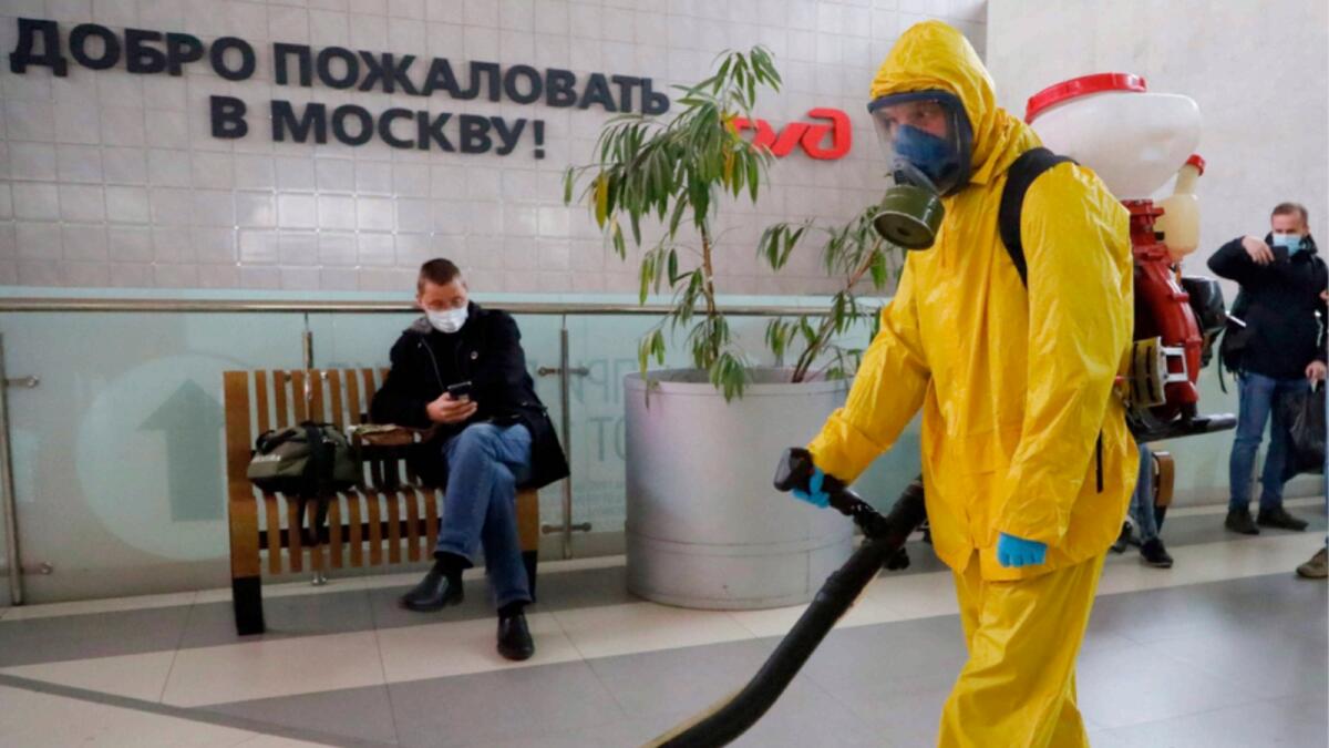 An employee of the Federal State Center for Special Risk Rescue Operations of Russia Emergency Situations disinfects Leningradsky railway station in Moscow. — AP