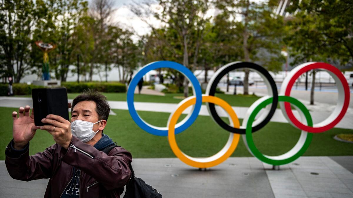 A man takes pictures in front of the Olympic Rings outside the Japan Olympic Museum in Tokyo on March 20, 2021. — AFP