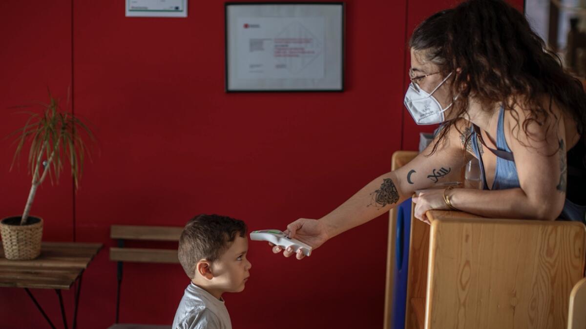 Hugo, 3, has his temperature taken by a teacher as he arrives at Cobi kindergarten in Barcelona, Spain. Photo: AP(Research: Mohammad Thanweeruddin/Khaleej Times)