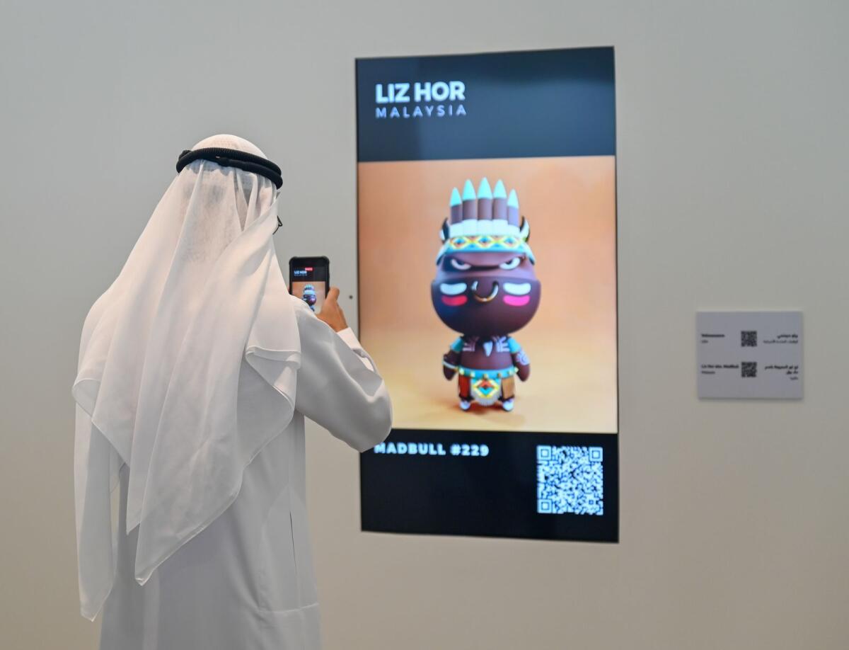 A visitor take photos of the digital artwork displayed at Sharjah’s first NFT art exhibition, “Gateway to the Metaverse’’ hosted by House of Wisdom - Photo by M. Sajjad