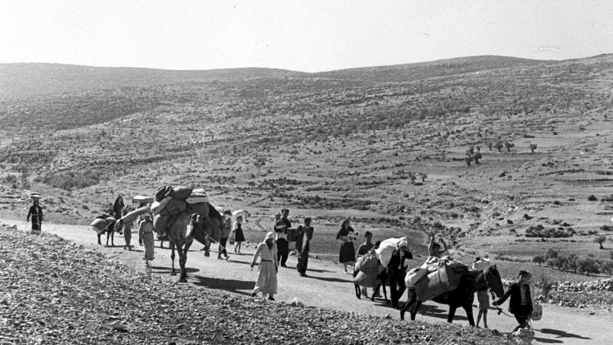 A group of Arab refugees walks along a road from Jerusalem to Lebanon, carrying their children and belongings with them on November 9, 1948. — AP file