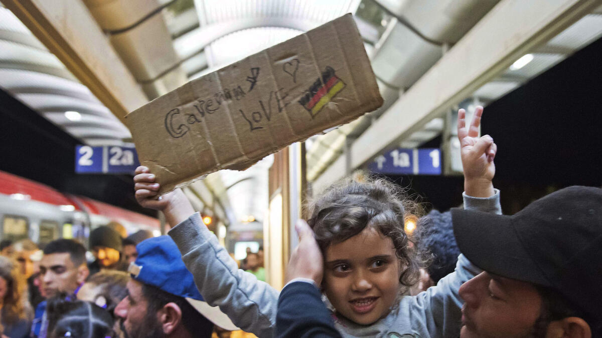 A migrant girl holds a sign expressing her love to Germany as she arrives at the train station in Saalfeld, central Germany, Saturday, Sept. 5, 2015. (AP photo)