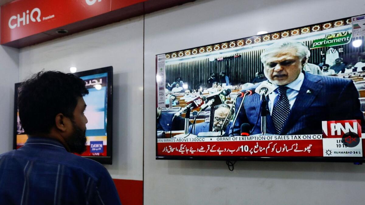 A salesman looks at a television screen showing the Pakistan's Finance Minister Ishaq Dar presenting the budget for the 2023/24 fiscal year in the parliament in Islamabad, at a shop in Karachi. – Reuters