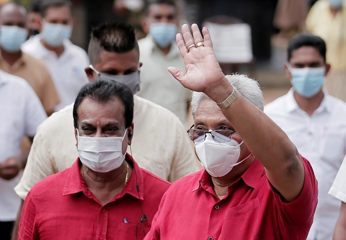 Sri Lanka's President Gotabaya Rajapaksa wears a protective mask as he waves to supporters while leaving a polling station.