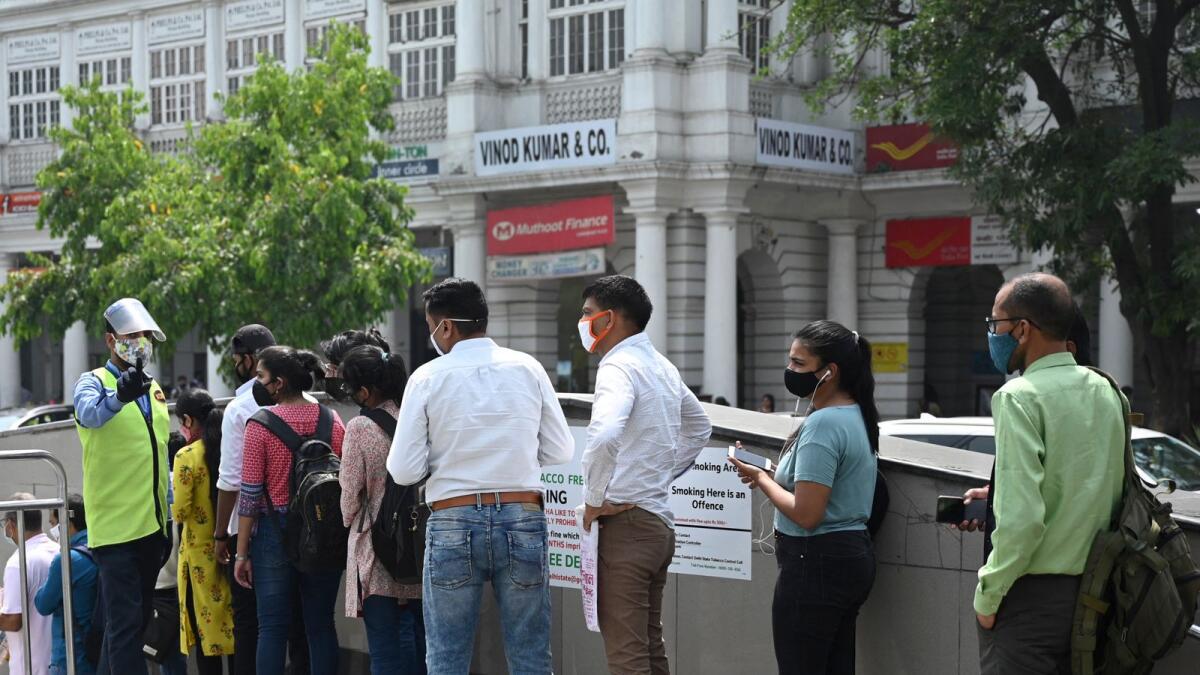Commuters stand in a queue outside a metro station in small groups as a preventive measure against the Covid-19 in Delhi. Photo: AFP