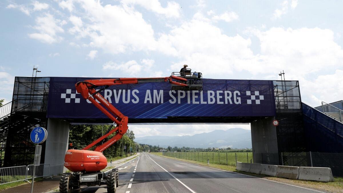 Workers fix a banner on a bridge next to the Formula One race track in Spielberg, Austria, on Wednesday. - Reuters
