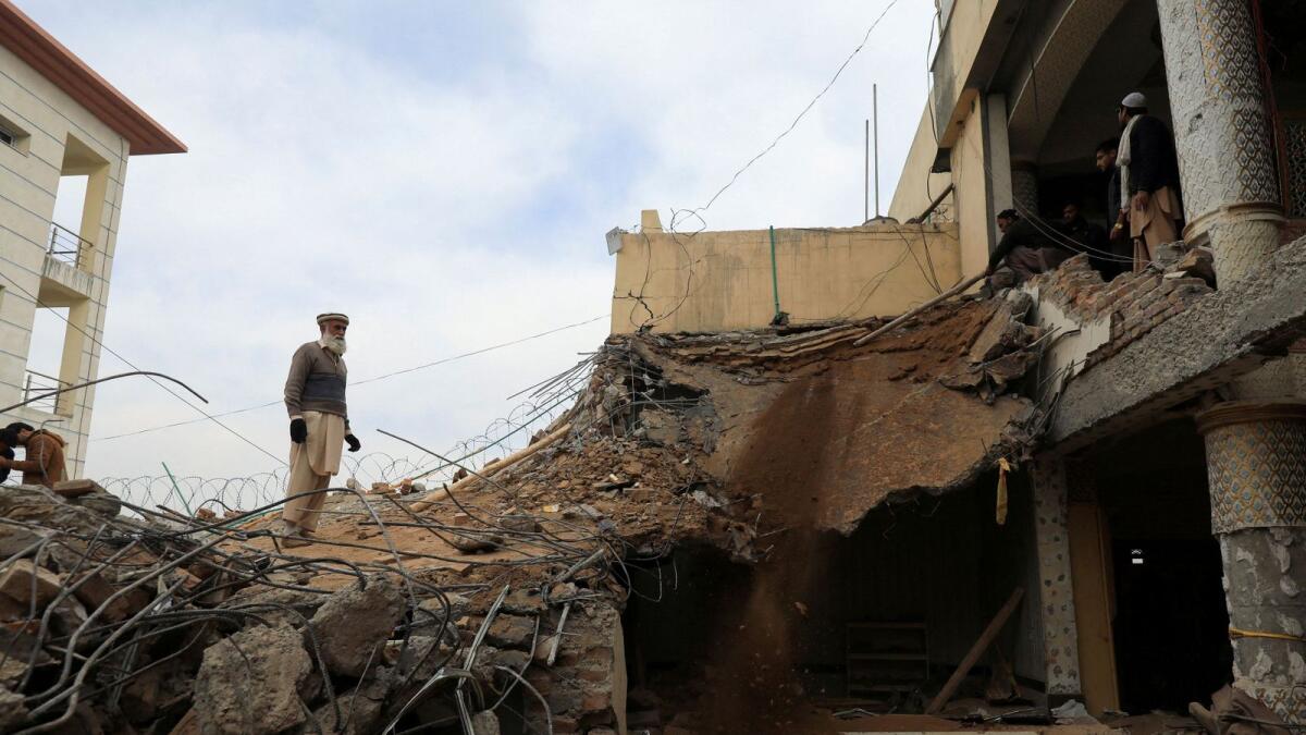 A man stands amidst the debris, days after the suicide blast in the mosque in Peshawar. — Reuters