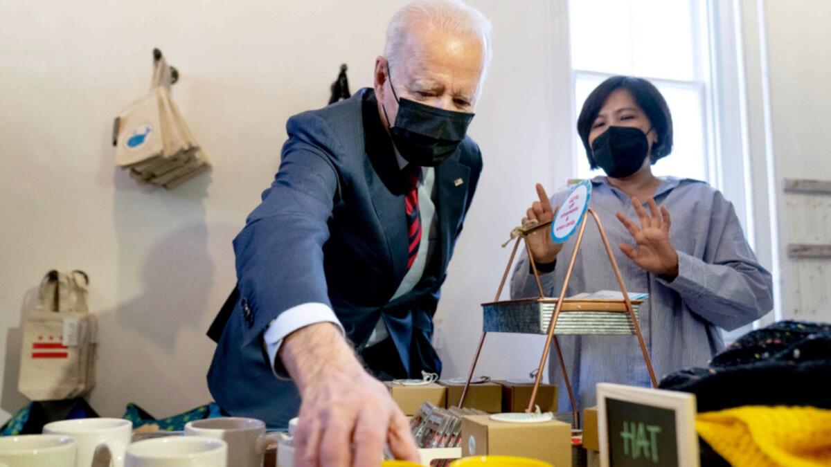 Owner Viboonrattana 'Moo' Honey watches as President Joe Biden picks up a Vice President Kamala Harris mug as he visits the Honey Made store in Washington. — AP