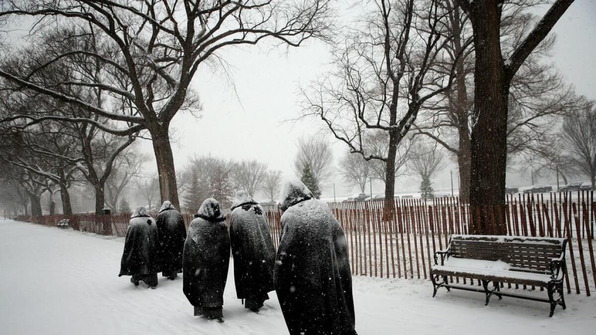 Nuns from the Fraternite Notre-Dame in Chicago, Illinois are covered in newly fallen snow as they walk along Constitution Avenue while snow begins to accumulate in Washington, DC. -AFP