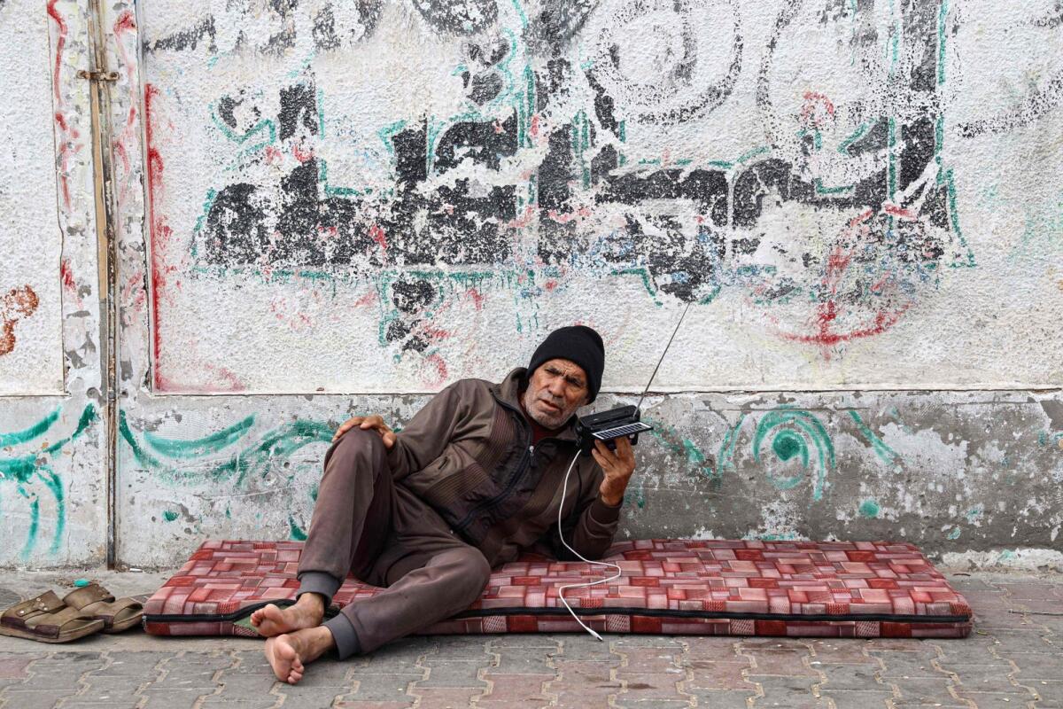 A Palestinian old man listens to his radio in a refugee camp in Rafah in the southern Gaza Strip on December 17. — AFP