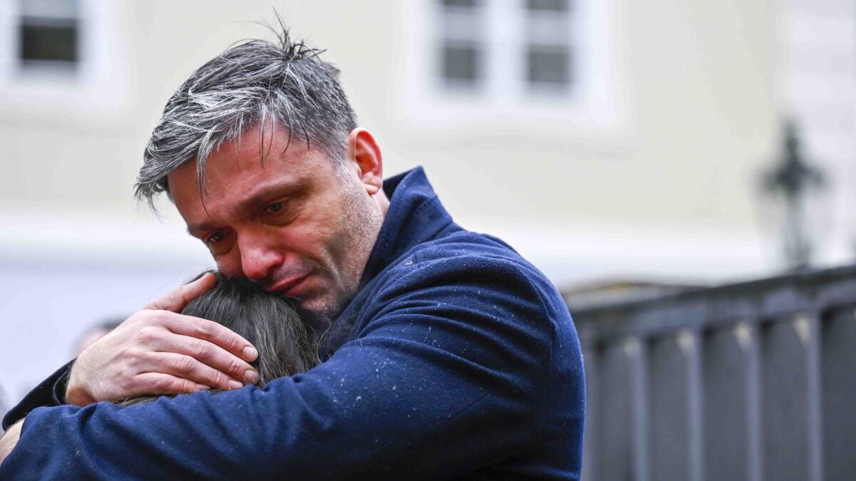 Mourners hug outside the headquarters of Charles University after a mass shooting in Prague. — AP