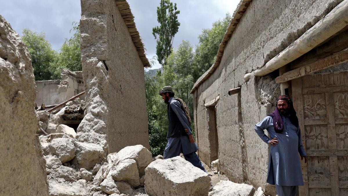 Afghan men stand on the debris of their house that was damaged by an earthquake in Gayan, Afghanistan, June 23, 2022. Picture taken June 23, 2022. REUTERS/Ali Khara