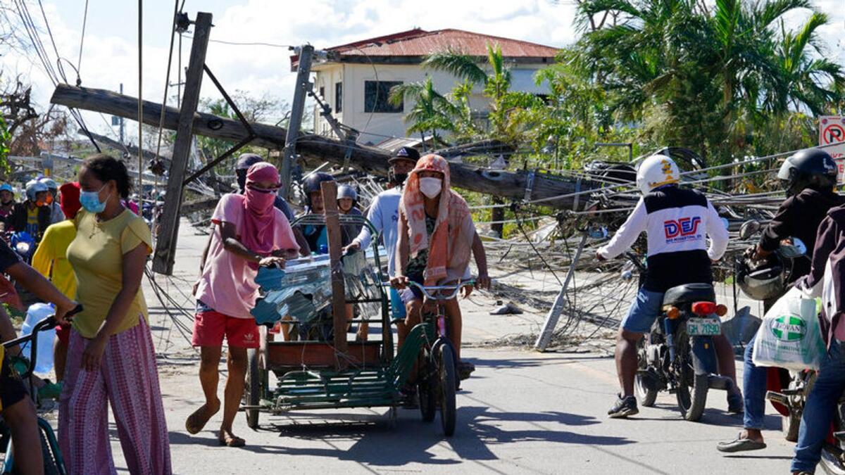 Residents pass by toppled electrical posts due to Typhoon Rai in Cebu province, central Philippines on Monday Dec. 20, 2021. Photo: AP