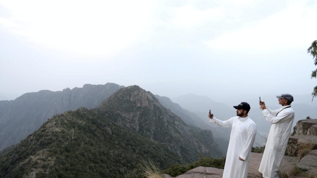 Saudi men take pictures at the Al Souda mountain, as the summer season kicks off with health precautions amid the coronavirus disease (Covid-19) outbreak, in an effort to boost internal tourism after the pandemic in Abha, Saudi Arabia. Photo: Reuters
