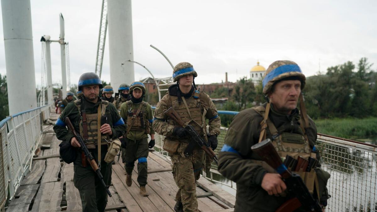 Ukrainian servicemen cross a footbridge in the recaptured area in Izium –AP